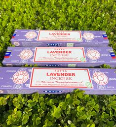 three lavender incense sticks sitting on top of green bushes