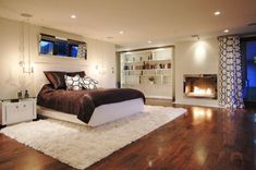 a bedroom with a bed, fireplace and large windows in it's center area