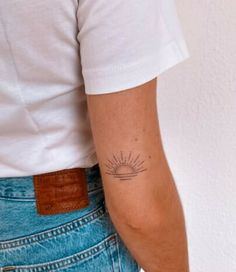 a person with a sun tattoo on their left arm and the other hand behind her back