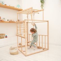 a young child playing in a wooden structure with ropes and ladders on the floor