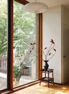 a vase with some flowers in it sitting on a table next to a large window