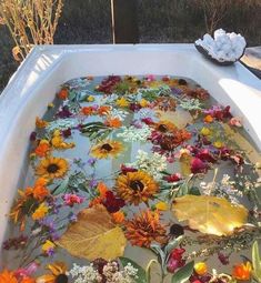 an outdoor bathtub filled with flowers and leaves