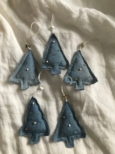 four blue christmas trees hanging from strings on a white sheet