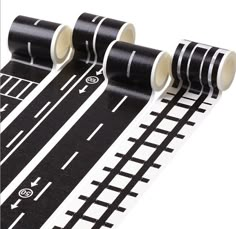 three rolls of black and white tape are next to each other on a track with an arrow