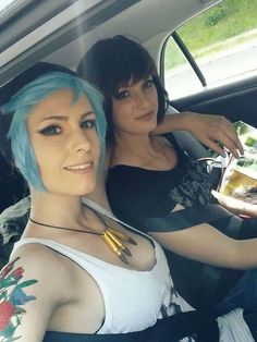 two women sitting in the back seat of a car with blue hair and tattoos on their arms