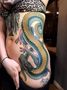 a woman's stomach with a colorful tattoo design on her belly and an image of a lizard