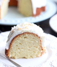 a slice of cake with white frosting on a plate next to another piece of cake