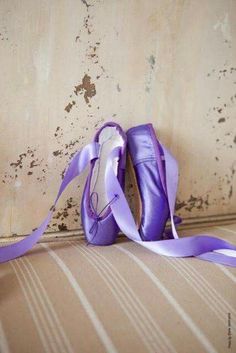 a pair of purple ballet shoes sitting on top of a floor next to a wall