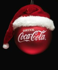 a coca - cola ornament hanging from a christmas tree with a santa hat on it