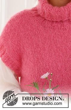 a close up of a person wearing a pink sweater with flowers on the front and bottom