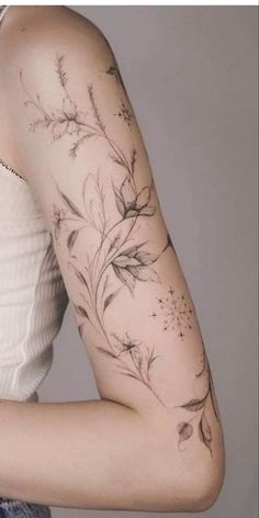 a woman's arm with flowers and leaves tattooed on the back of her arm