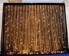 a curtain with lights on it in front of a blue carpeted floor and white walls