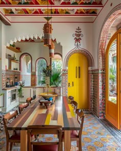 a dining room table and chairs in front of a yellow door with an arched window