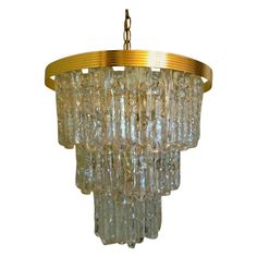 a chandelier made out of glass beads hanging from a brass frame and chain