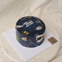 a space themed birthday cake on top of a white plate with a name tag in front of it