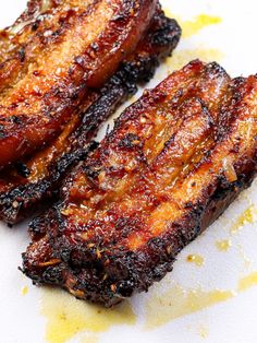 two pieces of grilled meat sitting on top of a white plate next to a knife