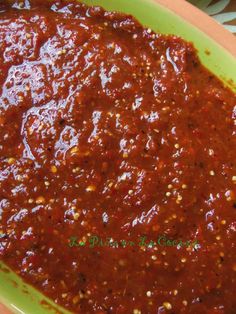 a green bowl filled with sauce on top of a table