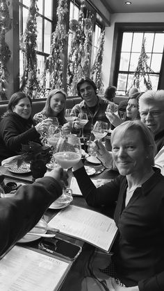 a group of people sitting at a table with wine glasses in their hands and papers on the table