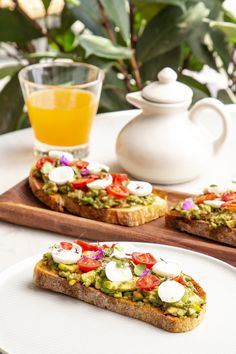 two pieces of bread with toppings sit on a plate next to a glass of orange juice