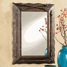 a mirror and vase with flowers in it on a wall next to a blue vase