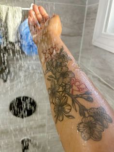 a person's arm with flowers on it and water coming from the faucet