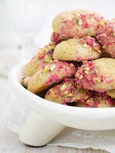 a white bowl filled with pink and yellow sprinkles on top of a table