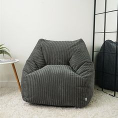 a grey corded bean bag chair next to a white rug