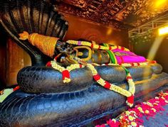 a large buddha statue sitting on top of a wooden bench next to a flower covered floor