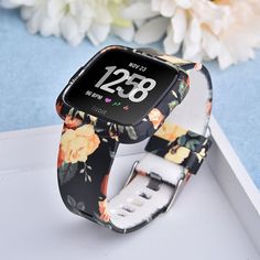 an apple watch with flowers on it sitting in front of a flowery background and the time displayed