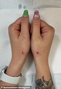 two hands with small tattoos on their fingers