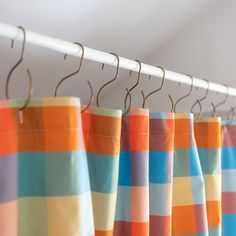 multicolored curtains are hanging on a white rod and hang from the ceiling in front of them