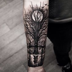 a man's arm with a black and white tattoo on it, which has an image of trees in the background