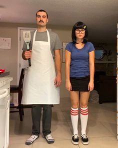 a man and woman in aprons standing next to each other with utensils