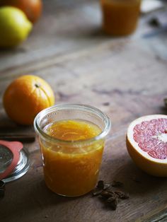 grapefruit and orange juice in a jar on a wooden table next to other fruit