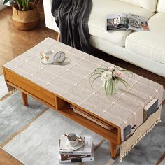 a coffee table with two cups on it in front of a white couch and rug