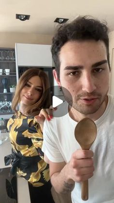 a man holding a wooden spoon in front of a woman