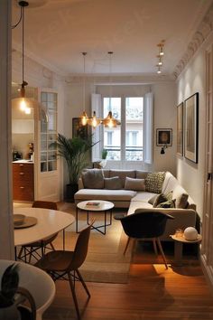 a living room filled with furniture next to a window on top of a hard wood floor