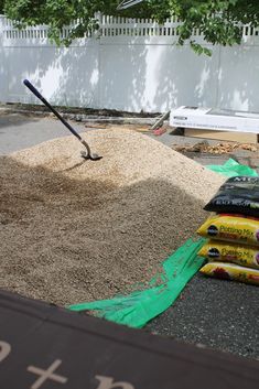 a pile of sand sitting on top of a parking lot next to a shovel and bag