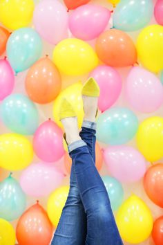 a woman's feet with yellow socks and blue jeans standing in front of balloons