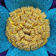 a blue bag filled with lots of gold beads on top of a purple and blue net