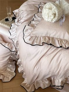 a white flower sitting on top of a bed with ruffles and pillows in it