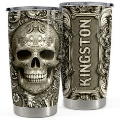 two stainless steel tumblers with skulls and ornate designs on the sides, one is silver