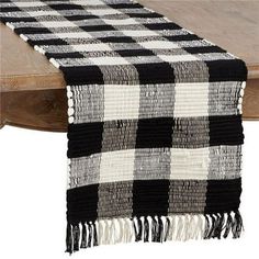 a black and white checkered table runner with fringes on top of a wooden table