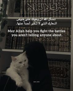 a white cat sitting on top of a person's lap in front of bookshelves