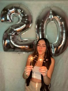 a woman holding sparklers in front of the number twenty