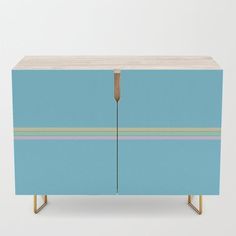 a blue cabinet with two doors and some gold legs on the bottom one has a striped design on it