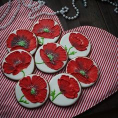 red and white cookies decorated with flowers on a striped tablecloth next to pearls, beads and necklaces