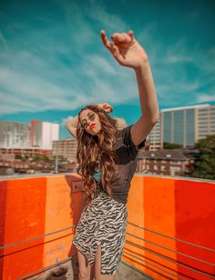 a woman standing on top of a roof with her arms in the air