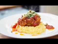 a white plate topped with meat covered in marinara sauce and mashed potato grits