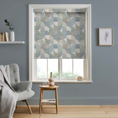 a living room with blue walls and a window covered in geometric patterned roman blind blinds